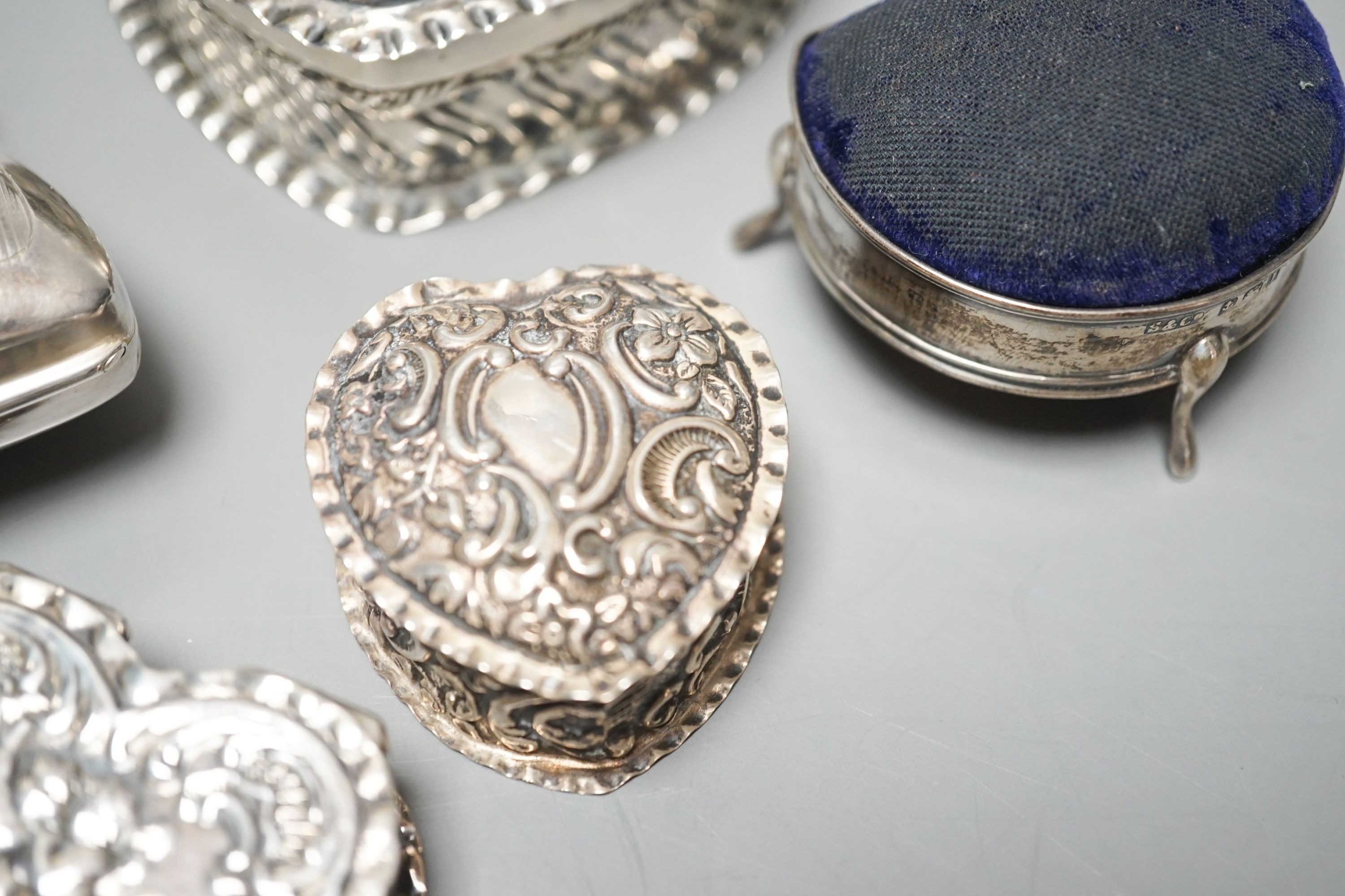 Four assorted silver or white metal heart shaped trinket boxes, largest 85mm a silver pin cushion and a silver purse.